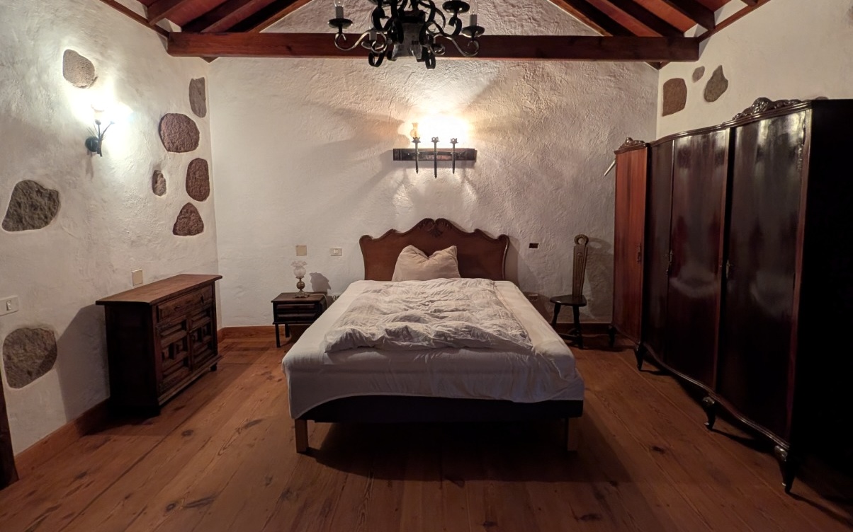 Schlafzimmer mit Holzbalken, Doppelbett und warmem Licht